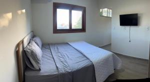 a bedroom with a bed with a window and a television at quarto stantard 5 in Guarapari