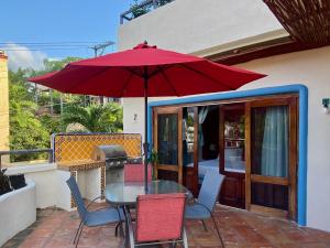 a table and chairs with a red umbrella on a patio at Casa MoJo - Whole house 7BR, heated pool, WiFi in Sayulita