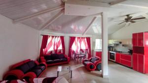 een woonkamer met rode meubels en rode gordijnen bij Ecotropicfarmhouse in Cerro Azul