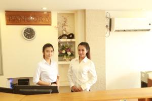 twee vrouwen in witte shirts staan in een kamer bij Pandora Motel in Yangon
