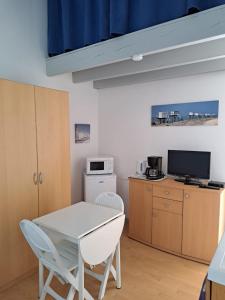 een kleine keuken met een witte tafel en een magnetron bij La Berguerie À Oléron in Dolus-d'Oléron