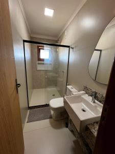 a bathroom with a toilet and a sink and a mirror at Quarto standard 7 pousada village in Guarapari