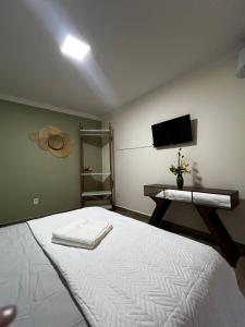 a bedroom with a large white bed and a television at Quarto standard 7 pousada village in Guarapari
