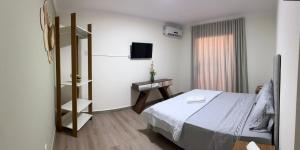 a hotel room with a bed and a television at Quarto standard 7 pousada village in Guarapari
