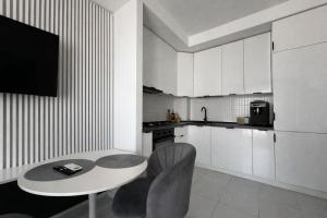a white kitchen with a table and chairs in a room at Nova Studio Bucharest #pool&parking in Ştefăneştii de Sus