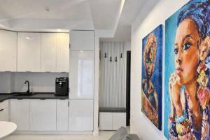 a kitchen with a large painting of a woman on the wall at Nova Studio Bucharest #pool&parking in Ştefăneştii de Sus