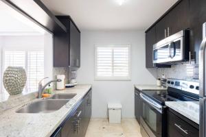 a kitchen with black cabinets and a sink at Playa Blanca Condo in Tijuana