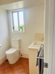 a bathroom with a toilet and a sink and a window at Coastal Calm in Normanville +24 photos