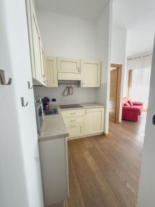 a kitchen with white cabinets and wooden floors at Bilocale sulle piste da sci in Pila