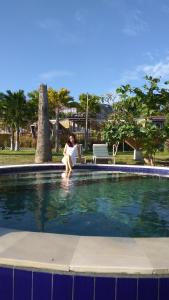 a woman sitting on a bench next to a swimming pool at Bali Umah Tinjung in Tulamben