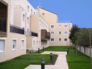 クレテイユにあるセジュール＆アフェール クレテイユ ル マジステルの2棟の建物の間に芝生の庭があるアパートメント複合施設