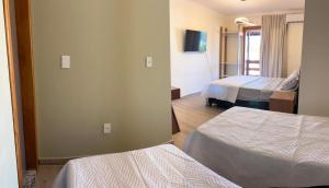 a hotel room with two beds and a tv at quarto quadruplo 8 in Guarapari