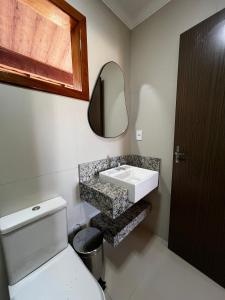 a bathroom with a sink and a toilet and a mirror at quarto quadruplo 8 in Guarapari