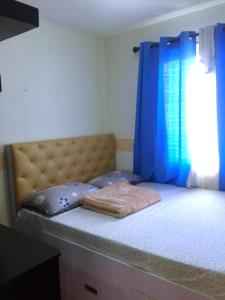 a bedroom with a bed with a blue curtain at Janna's Condo Hotel in Cebu City +7 photos