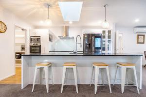 a kitchen with a large counter with three bar stools at Spacious 3BR with 2 carpark in Lincoln