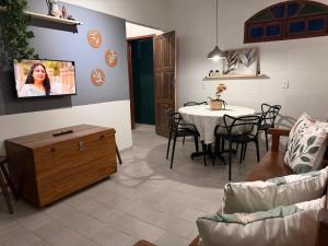 a living room with a table and a tv on a wall at Casa c 3 Suítes 4 banheiros 4 quartos climatizados a passos da Praia, Centro e comércios in Alcobaça