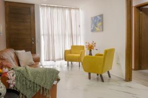 a living room with two yellow chairs and a couch at Santuario De Luna, Departamento in Cholula