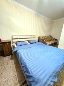 a bedroom with a large blue bed and a couch at Аэропорт Астана 5 минут 1 in Astana