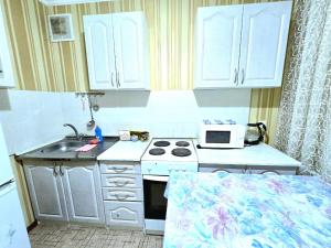 a small kitchen with a stove and a microwave at Аэропорт Астана 5 минут 1 in Astana