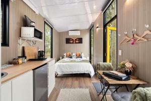 een slaapkamer in een tiny house met een bed en een tafel bij Inana Shanti by Tiny Away in Cooranbong