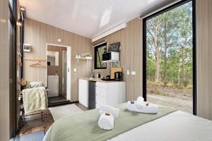 een slaapkamer met een bed met twee handdoeken erop bij Inana Shanti by Tiny Away in Cooranbong