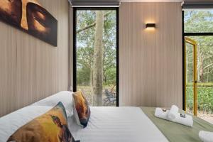 een slaapkamer met een bed en een groot raam bij Inana Shanti by Tiny Away in Cooranbong