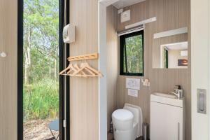een kleine badkamer met een toilet en een raam bij Inana Shanti by Tiny Away in Cooranbong