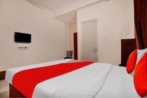 a bedroom with a red and white bed and a tv at Hotel O Sudipti Resort in Indore +26 photos