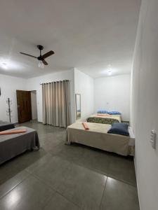 a bedroom with two beds and a ceiling fan at Hotel Pousa Vale Imperial in Aparecida