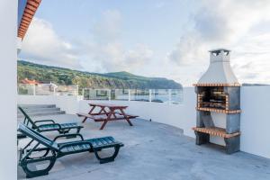 a fireplace on the roof of a house with a picnic table at Quo Mosteiros Sunset House in Mosteiros