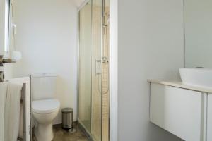 a bathroom with a toilet and a glass shower at Quo Mosteiros Sunset House in Mosteiros