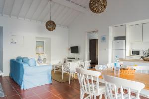 a dining room and living room with a table and chairs at Quo Mosteiros Sunset House in Mosteiros