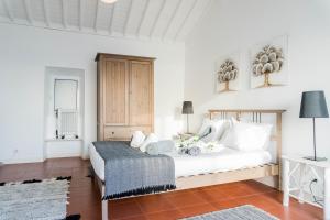 a white bedroom with a bed and a table at Quo Mosteiros Sunset House in Mosteiros