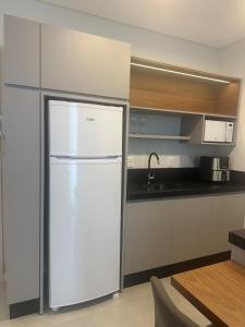 a kitchen with a white refrigerator and a sink at Flat novo próximo ao Hard Rock in Itapema