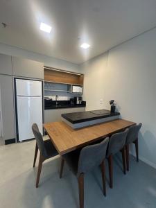 a kitchen with a wooden table and chairs at Flat novo próximo ao Hard Rock in Itapema +6 photos
