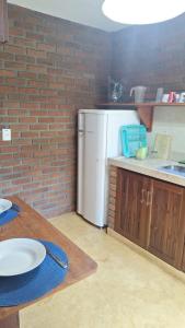 a kitchen with a white refrigerator and a brick wall at Edícula 2 quartos frente mar in Ilhéus +10 photos