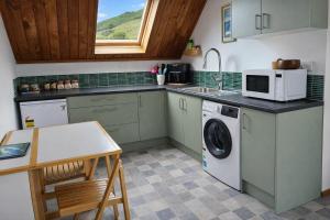 a kitchen with a washing machine and a microwave at Hill Top Hideaway - Self Contained Guest Suite with Private Spa in Pukerua Bay