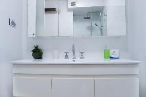 a white bathroom with a sink and a mirror at Central CBD High-Level Apartment with Views in Sydney +25 photos