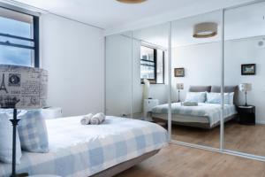 a white bedroom with two beds and a mirror at Central CBD High-Level Apartment with Views in Sydney