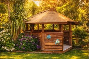 a wooden gazebo in a garden with flowers at Hill Top Hideaway - Self Contained Guest Suite with Private Spa in Pukerua Bay