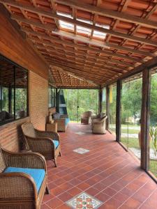 a covered patio with chairs and tables and windows at Casa da Cuca in Nova Friburgo