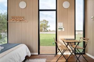 una camera da letto con un letto, un tavolo e delle sedie di Murray Haven Farm Stay by Tiny Away a Koonoomoo