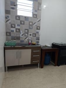 a kitchen with a counter and a sink and a table at Kitnet amplo in Santa Cruz Cabrália +1 photo