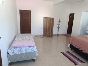 a room with two beds and a closet in it at Kitnet amplo in Santa Cruz Cabrália