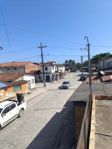 a city street with a white car parked on the road at Kitnet amplo in Santa Cruz Cabrália