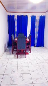 een eetkamer met blauwe gordijnen en een tafel en stoelen bij Papi House in Limbe