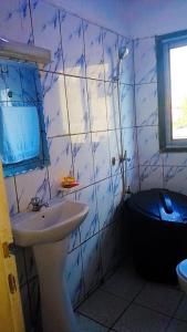 een blauw betegelde badkamer met een wastafel en een toilet bij Papi House in Limbe