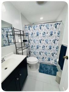 a bathroom with a toilet and a floral shower curtain at Nice private room with separate entrance in Port Richey +31 photos