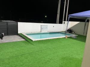 a swimming pool with green grass at night at CASA MARECHAL FRANCÊs in Marechal Deodoro