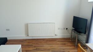 a living room with a flat screen tv and a radiator at City Sparrow - Upper Pad Nest in London